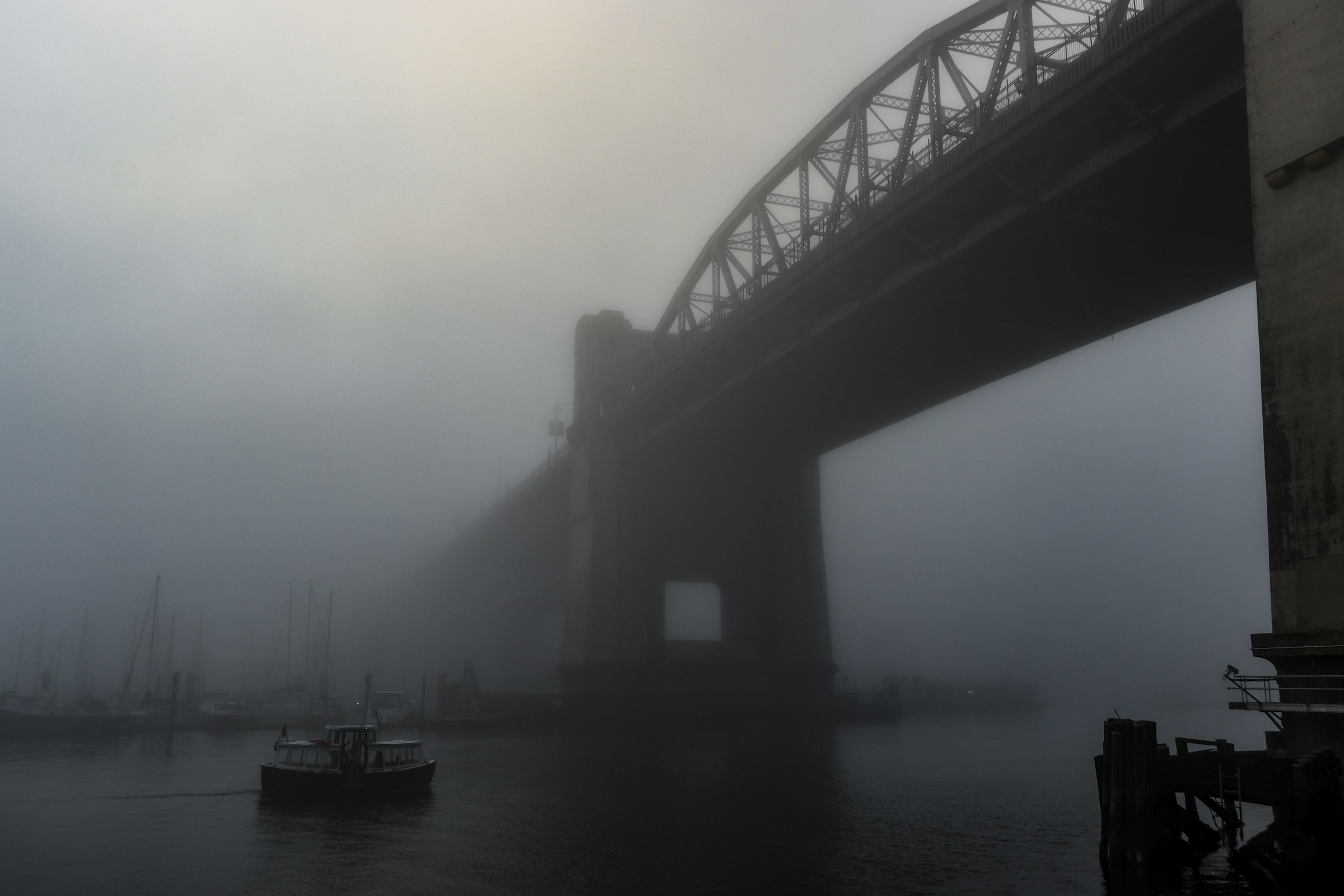 Burrard Street Bridge fades into fog above boats on False Creek.